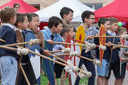 Groupe d’enfants participant à une activité collective avec boucliers et bâtons en extérieur